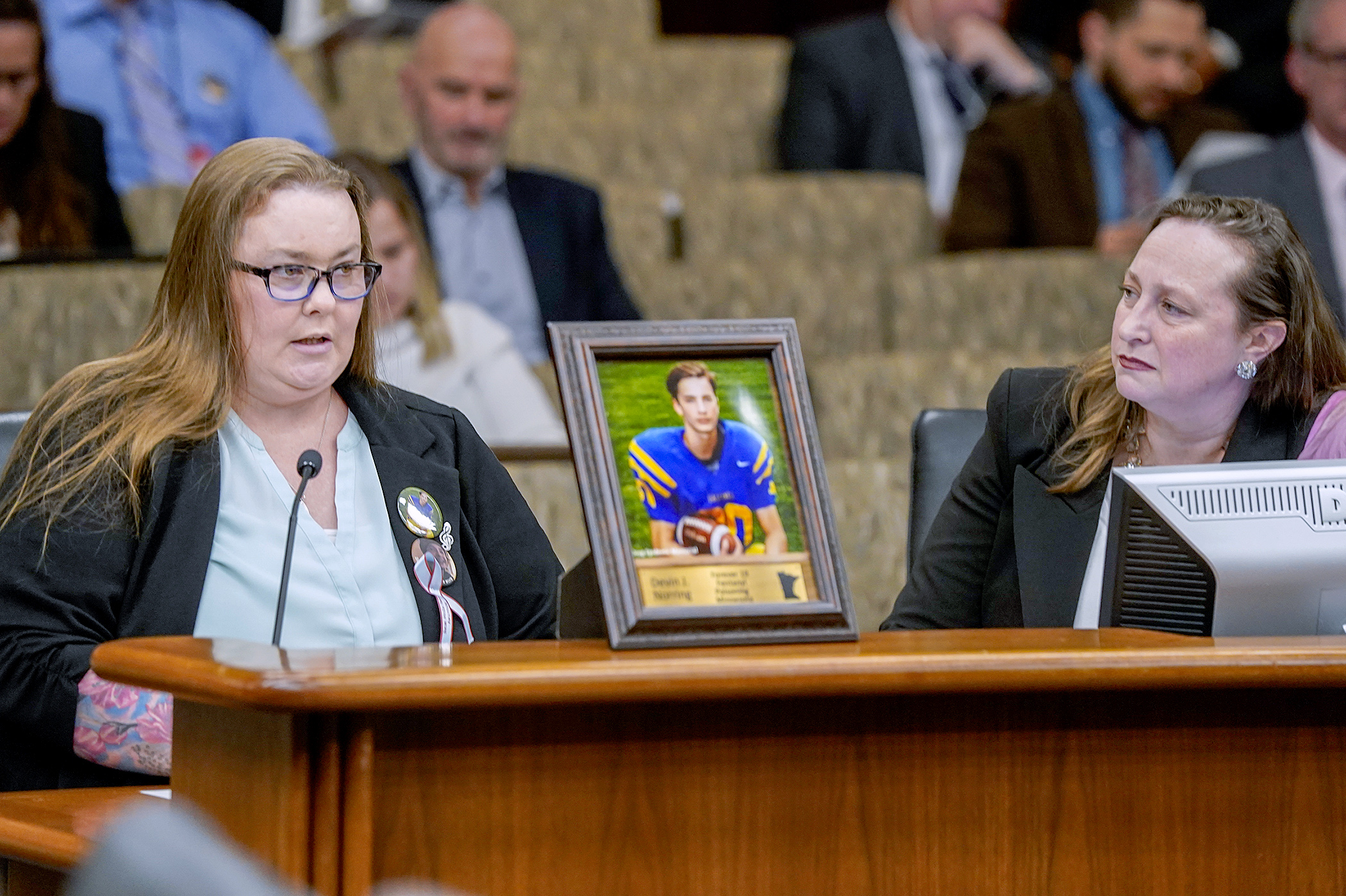 Bridgette Norring told lawmakers of her son, Devin, while testifying in support of HF2257. Devin died after purchasing a fentanyl pill through Snapchat he believed was Percocet. Rep. Kristin Bahner, right, sponsors the bill. (Photo by Michele Jokinen)
